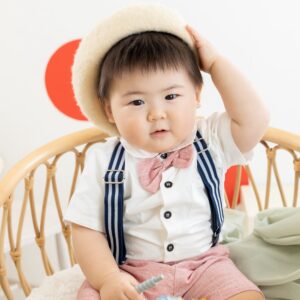 1歳の男の子が白いベレー帽、薄いピンクの蝶ネクタイがついたフォーマルな衣装着用写真