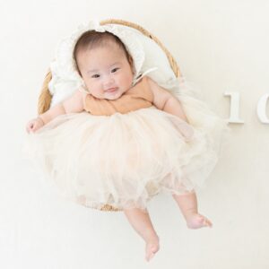 生後100日の赤ちゃんが寝転がってチュールドレスを着ている 衣装着用例の写真