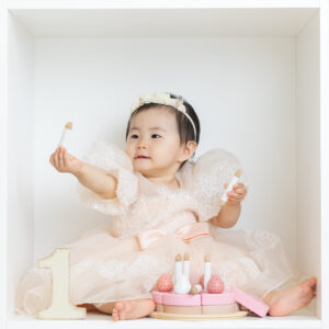 1歳の女の子がふんわりした薄いピンクのドレスを着ているお写真