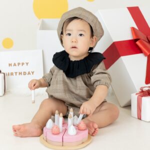ブラウンの千鳥格子柄のベレー帽、ロンパースを着た1歳の子どもが写っている写真